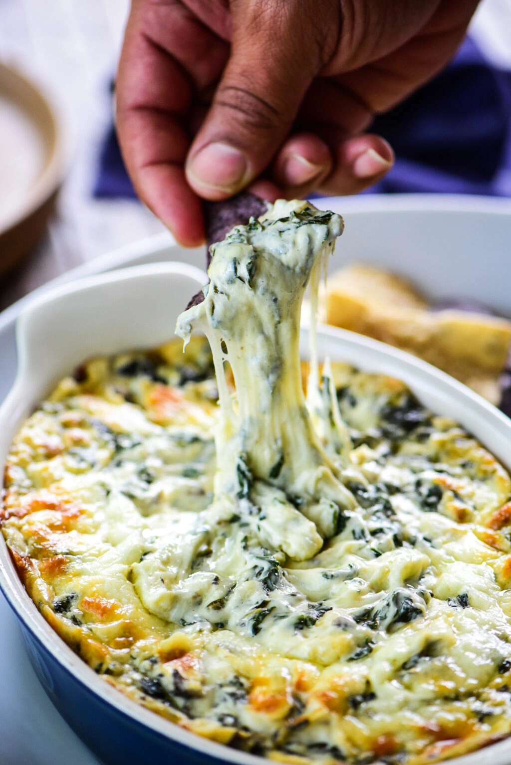 dipping tortilla chip in cheesy spinach dip