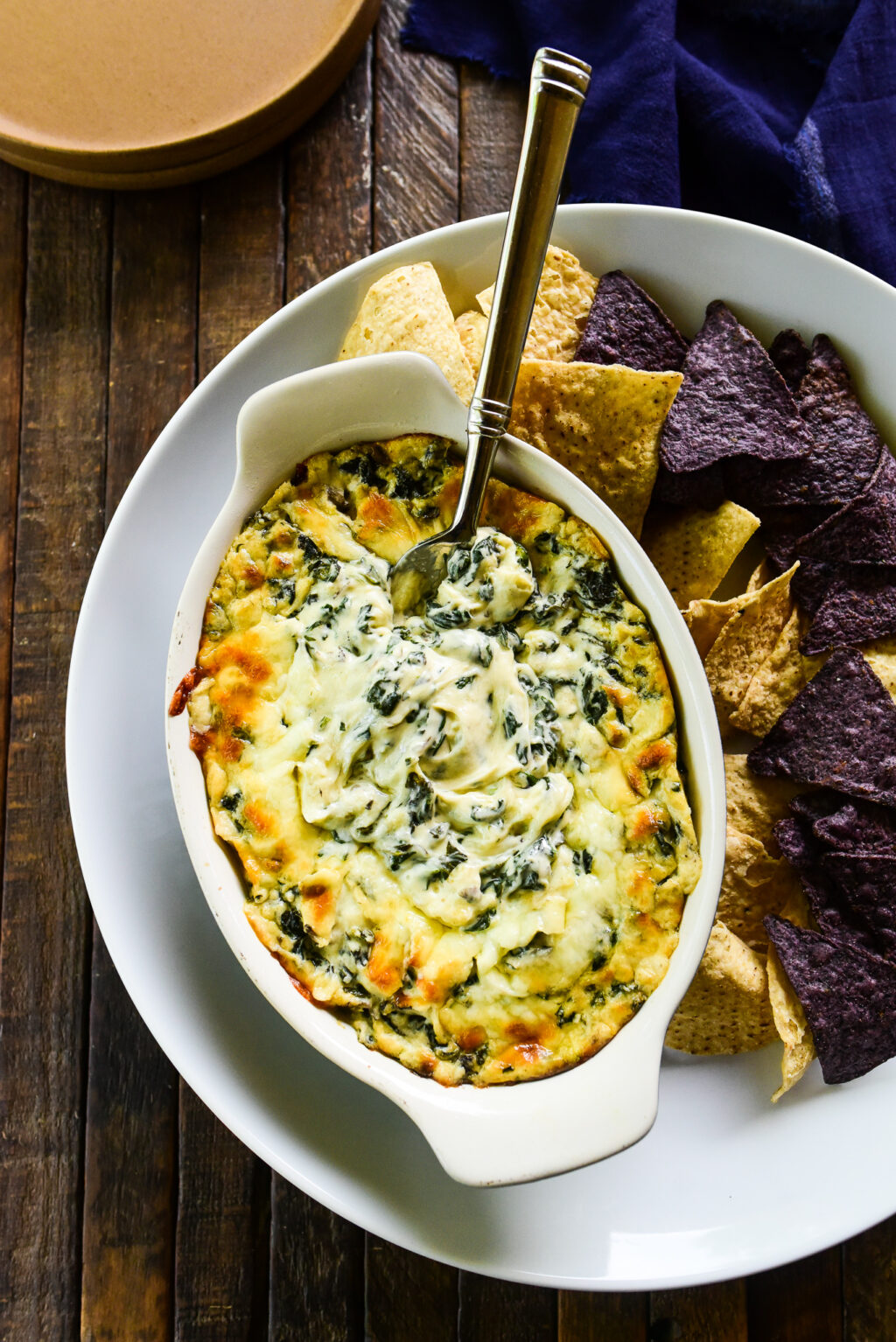 overhead shot of spinach dip with tortilla chips and serving plates