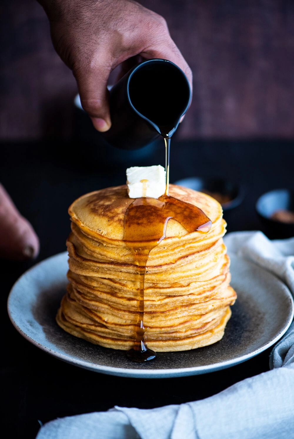 Pouring syrup on a stack of sweet potato pancakes
