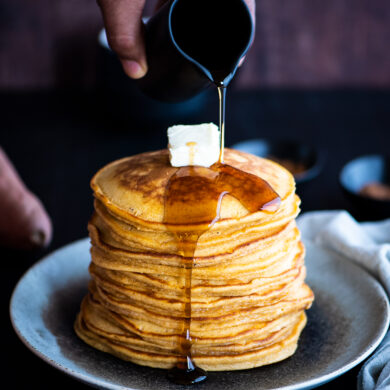 Pouring syrup on a stack of sweet potato pancakes