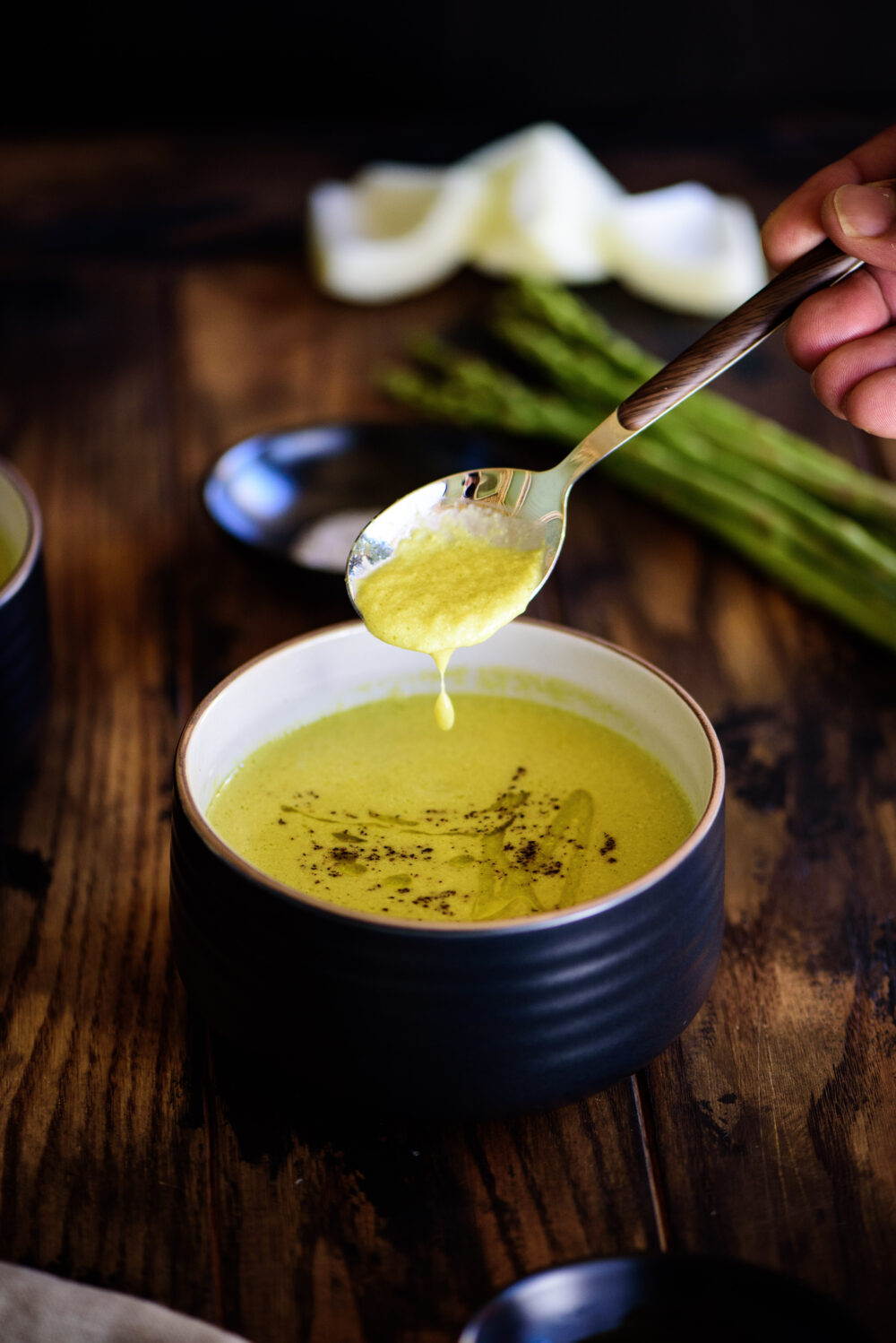 taking a spoonful of asparagus soup