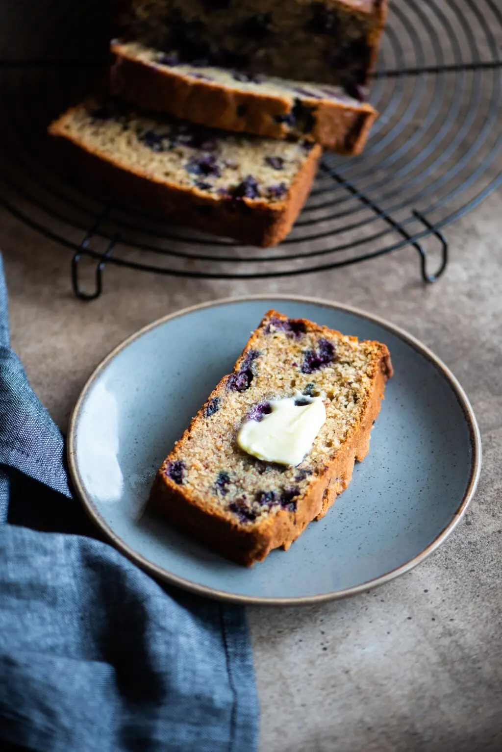slice of blueberry banana bread with butter on top