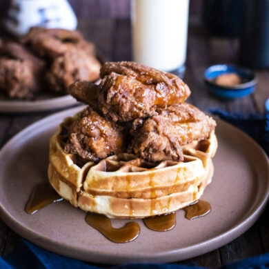 front picture of chicken and waffles on table with cup of eggnog
