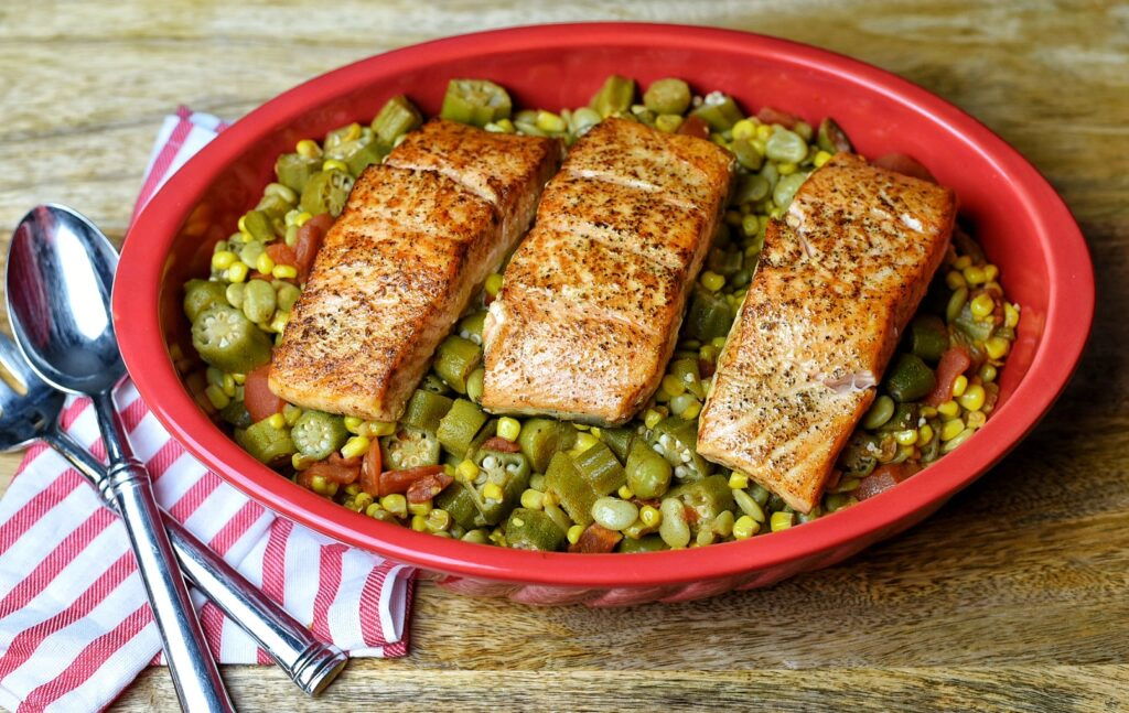 Pan Seared Creole Salmon sitting om a top a bed of Succotash