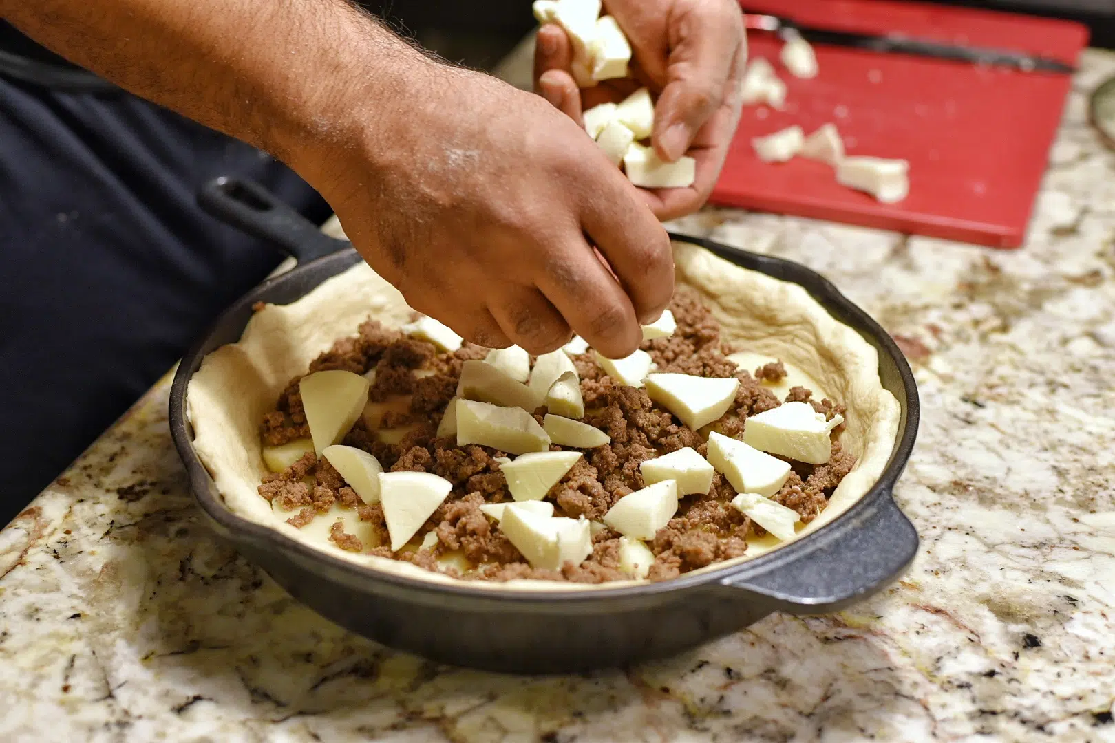 Adding the chopped mozzarella to the pizza