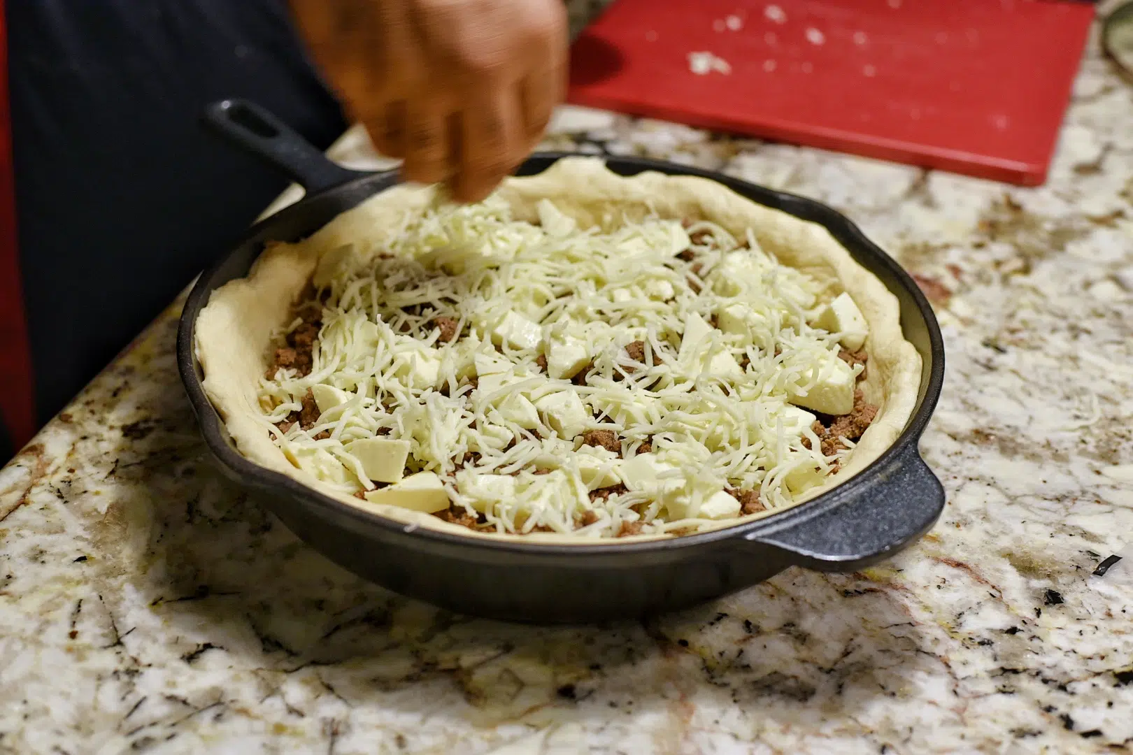 Adding the shredded mozzarella to the pizza