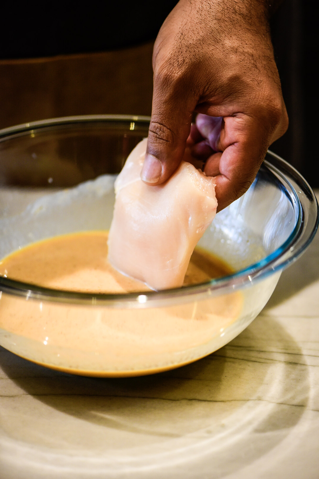 Dipping chicken breast in buttermilk marinade