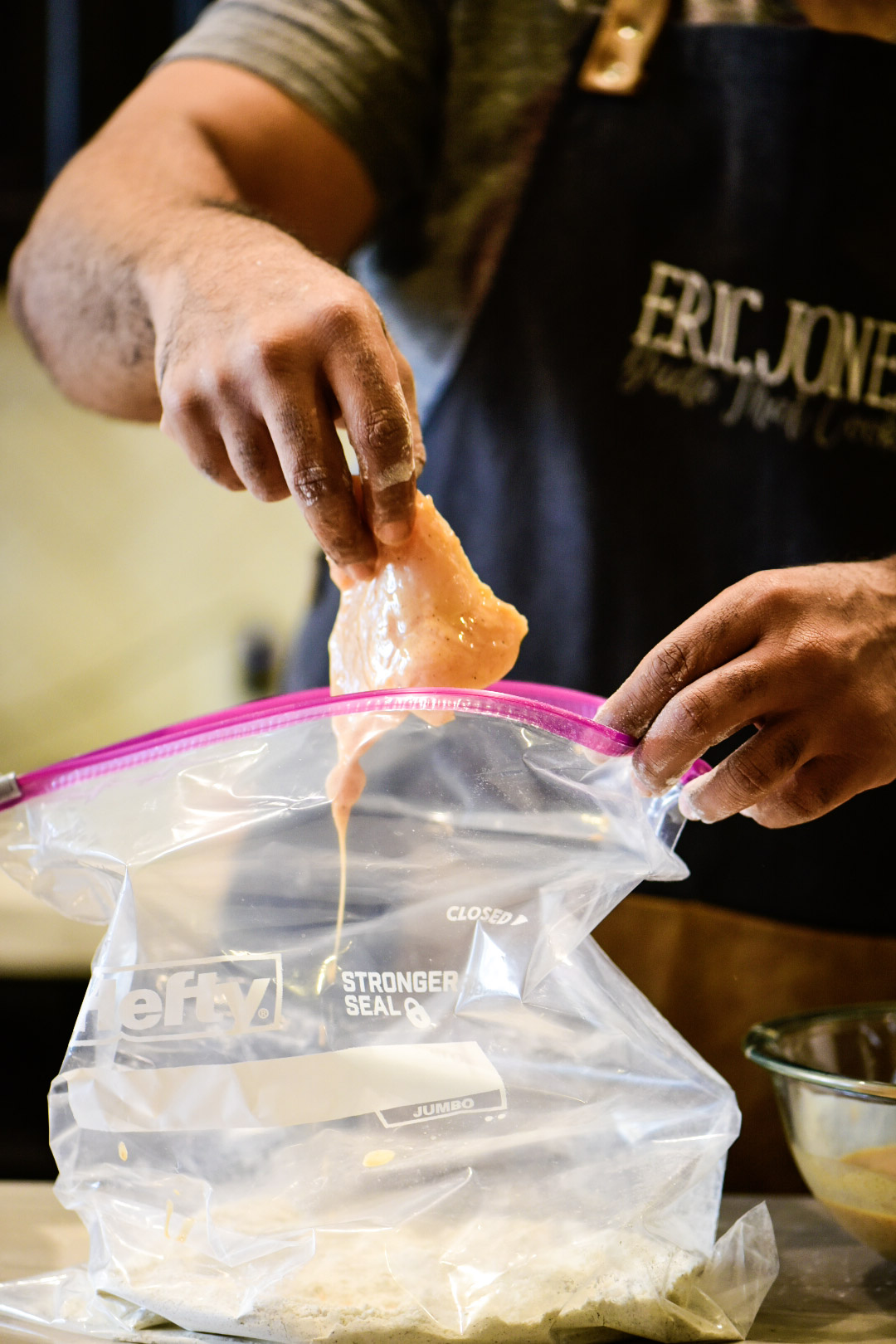 Adding marinated Cajun chicken to zip lock bag to coat with flour