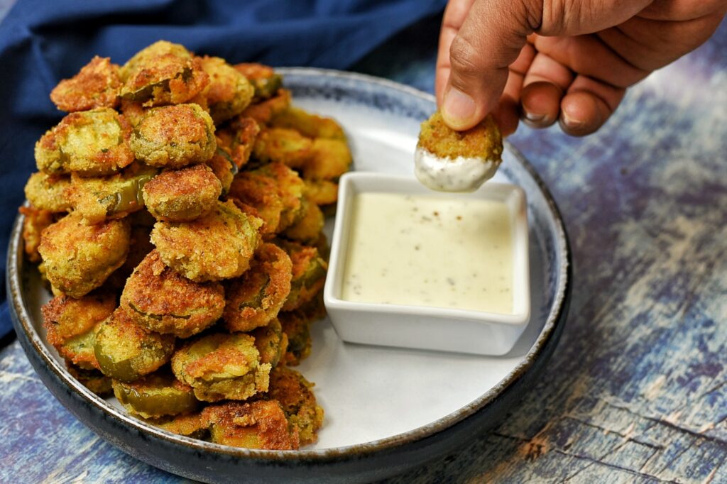 Dipping the fried pickles in ranch dressing.