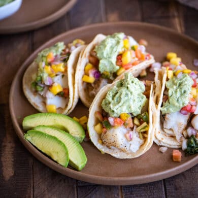 grilled fish tacos on a plate with sliced avocado