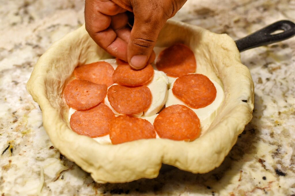 Adding the first layer of cheese and pepperoni