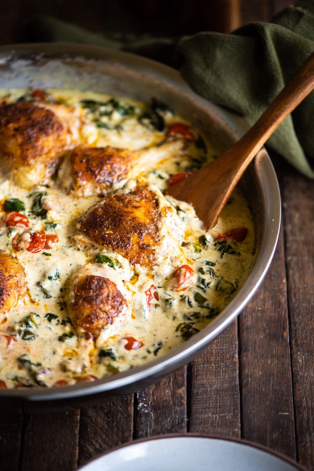 one skillet creamy tuscan chicken with wooden serving spoon