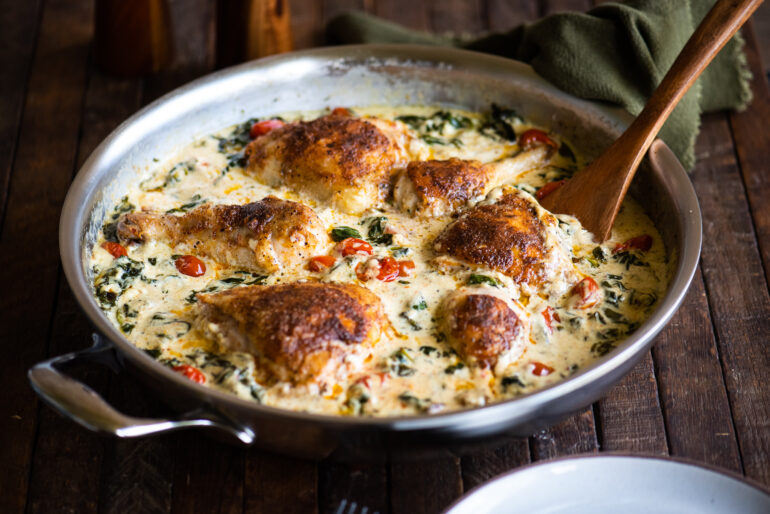 one skillet creamy tuscan chicken with wooden serving spoon