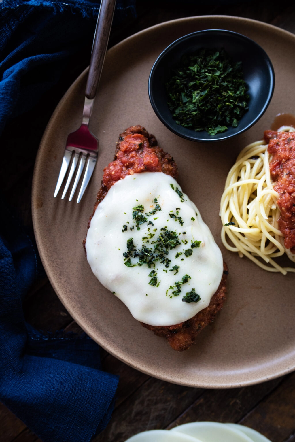 Plated chicken parmesan with a side of spaghetti and tomato sauce