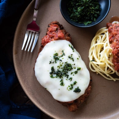 Plated chicken parmesan with a side of spaghetti and tomato sauce