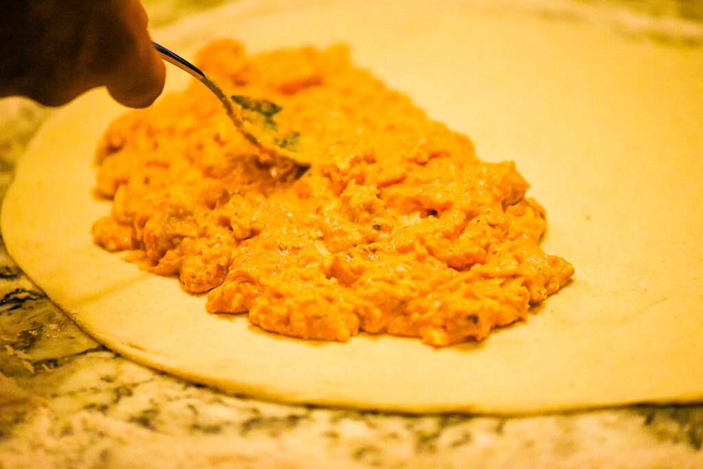 Adding buffalo chicken mixture to dough.