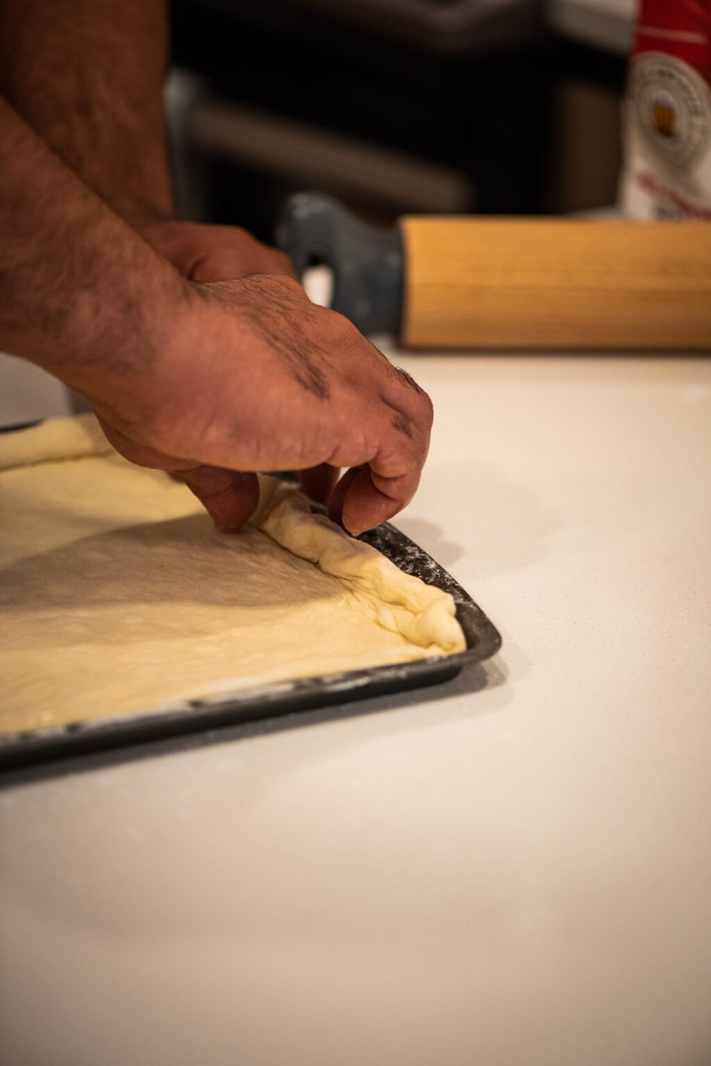 placing rolled pizza dough on baking sheet