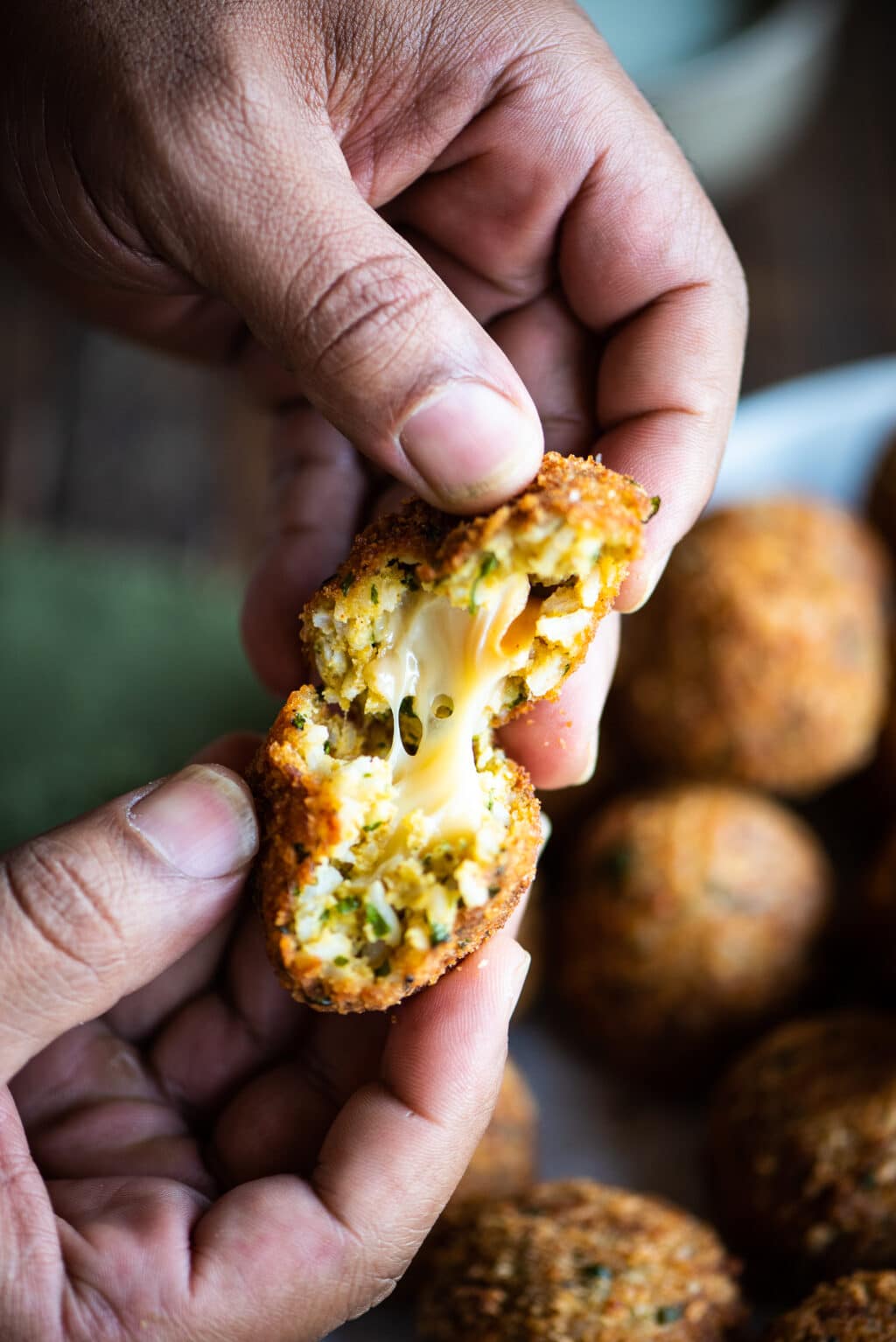 breaking arancini open and showing the melted cheese