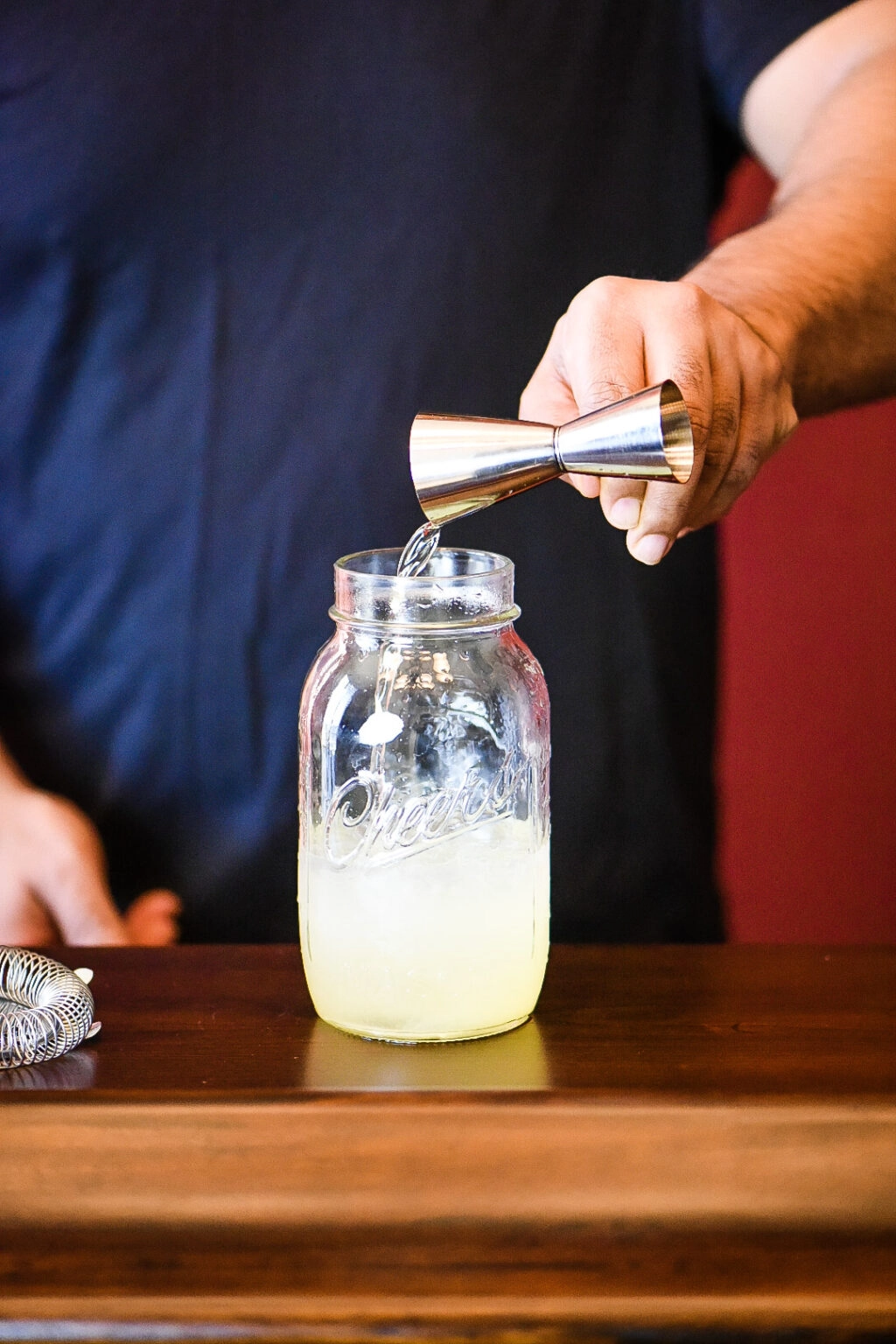 Adding ice and all cocktail ingredients to the cocktail shaker.