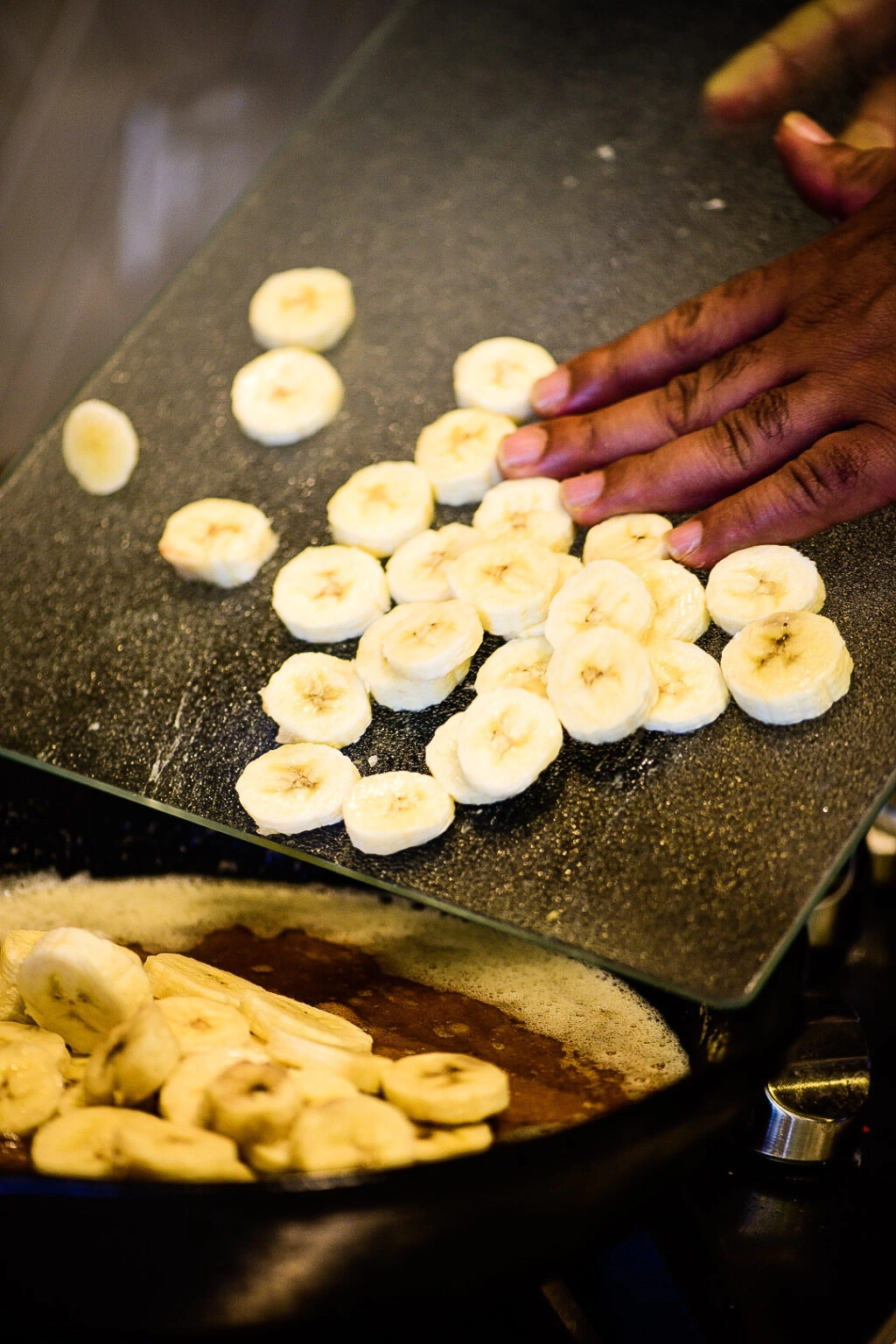 Adding sliced bananas to pan for bananas foster.