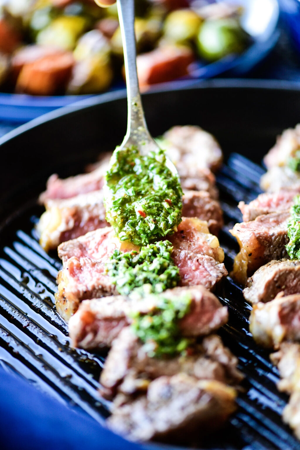 Placing chimichurri sauce on sliced new york strip loin