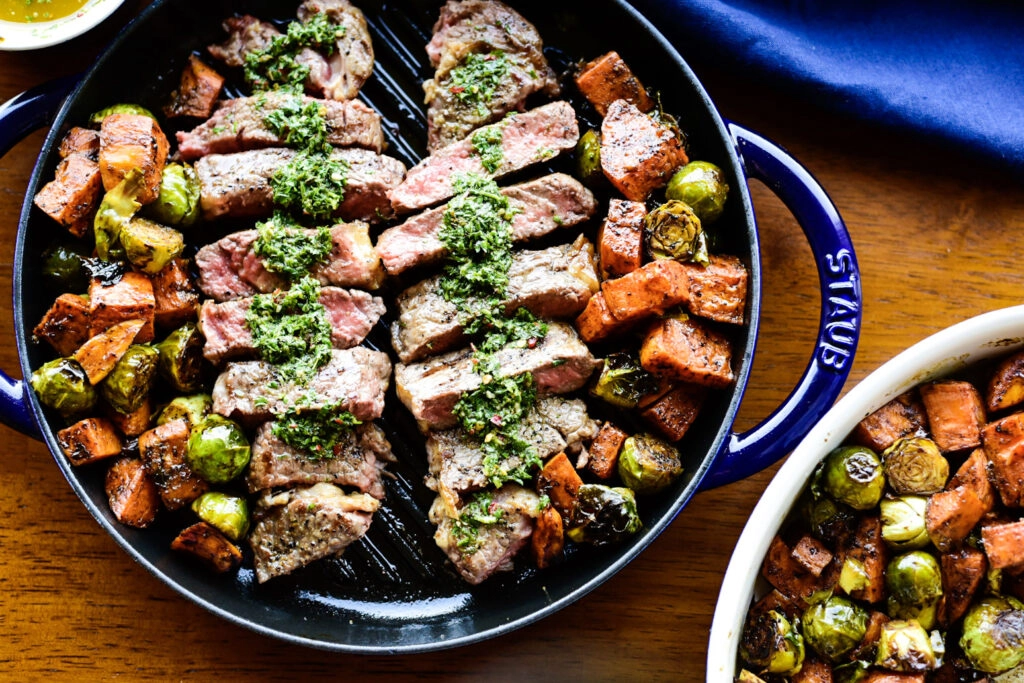 Overhead shot of sliced new york strip loin with chimichurri sauce