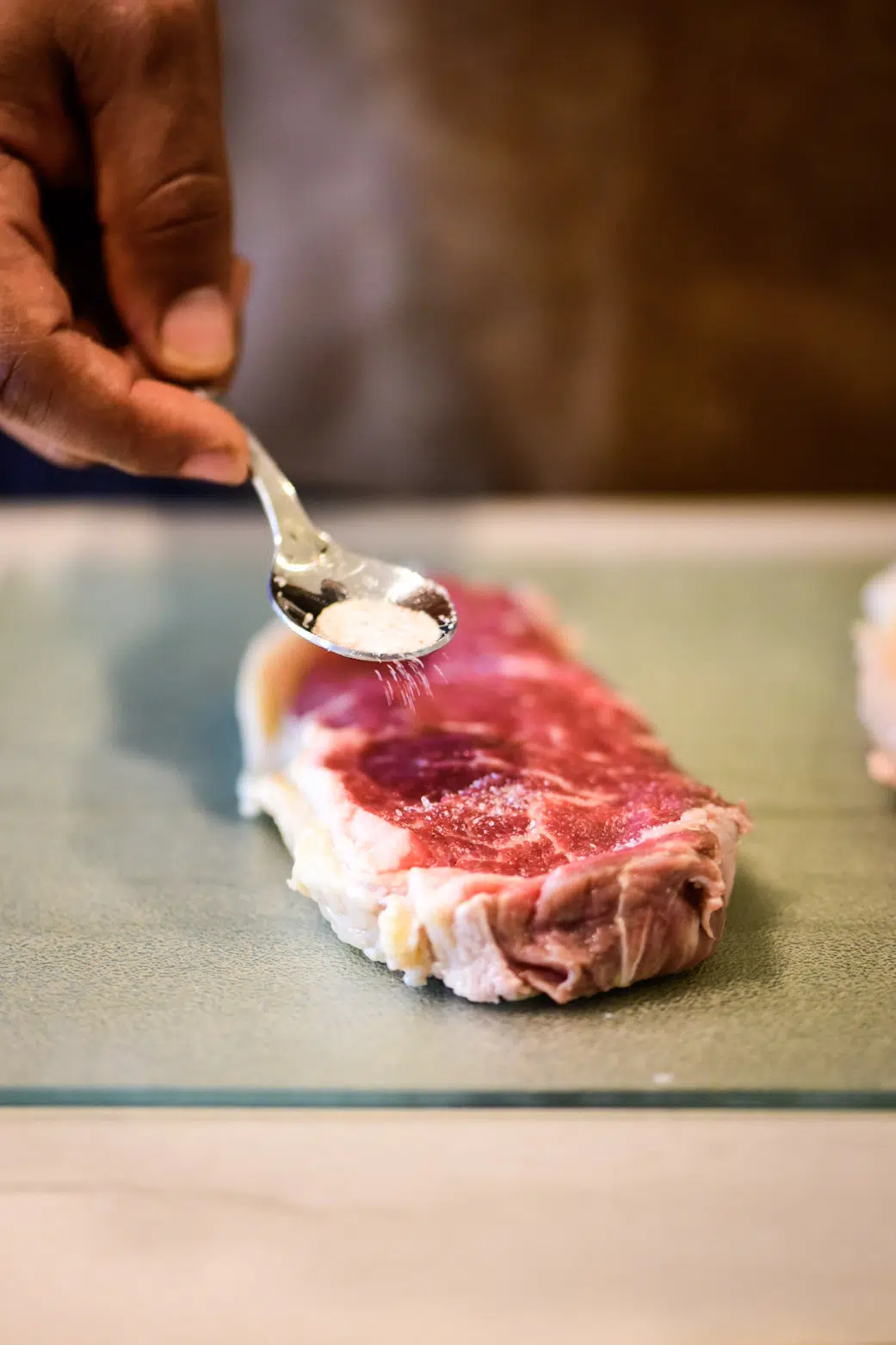 Adding salt to 8 oz. portions of strip loin