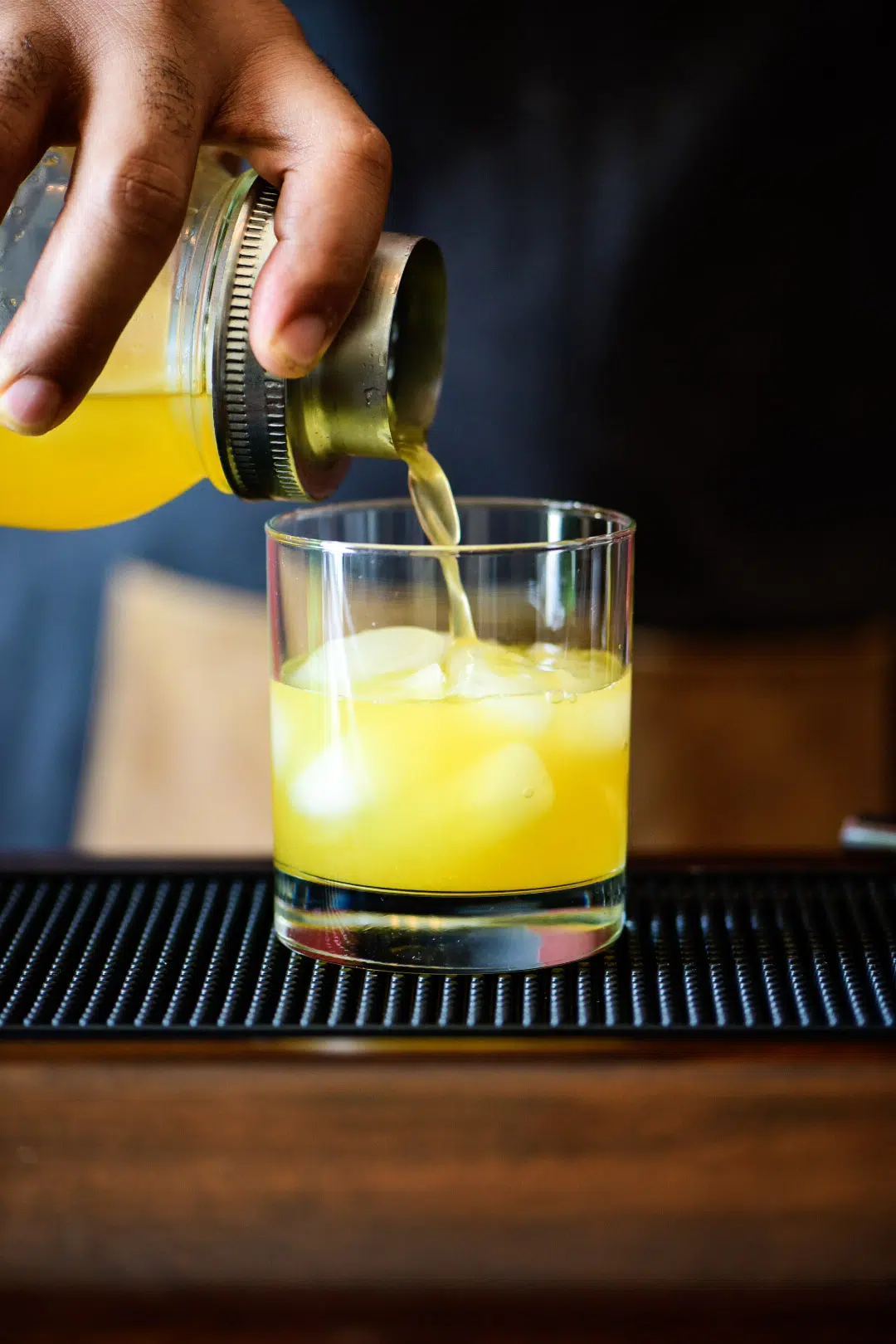 pouring shaken cocktail in iced glass for Mandarin Orange Crush Cocktail