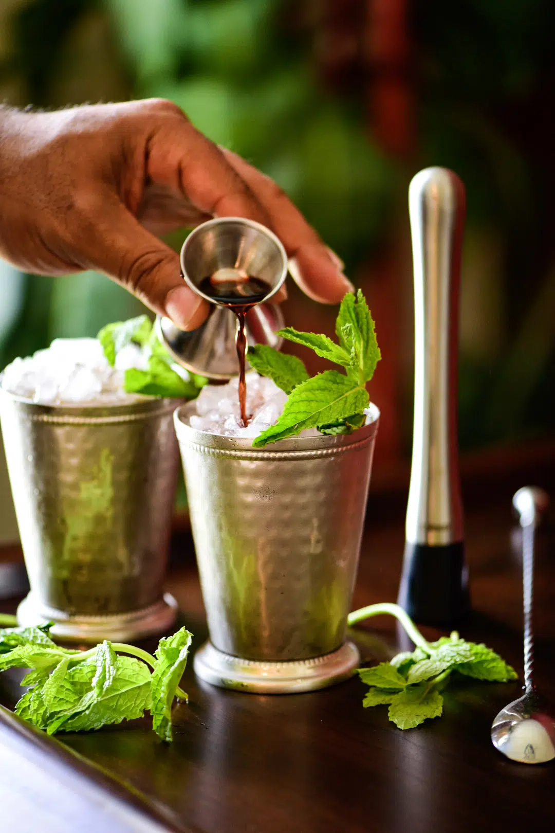 Topping off mint julep cocktail with blackberry liqueur