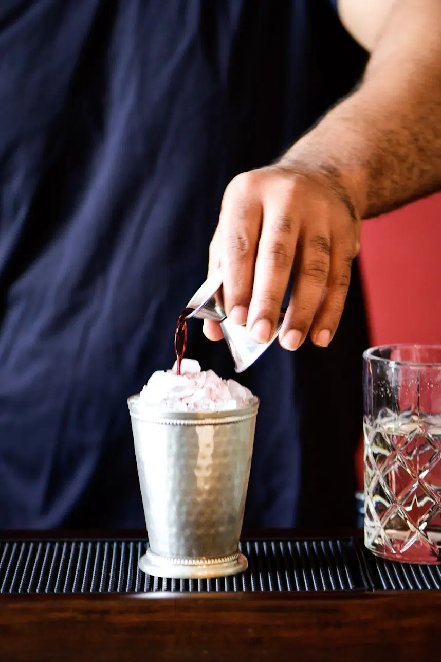 Pouring blackberry liqueur on top of cocktail