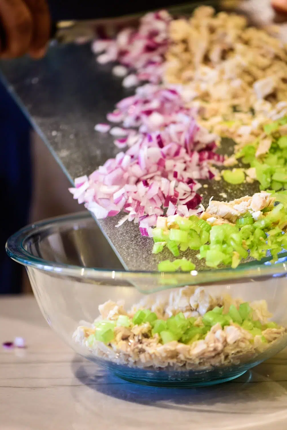 Adding chicken salad ingredients to a large bowl