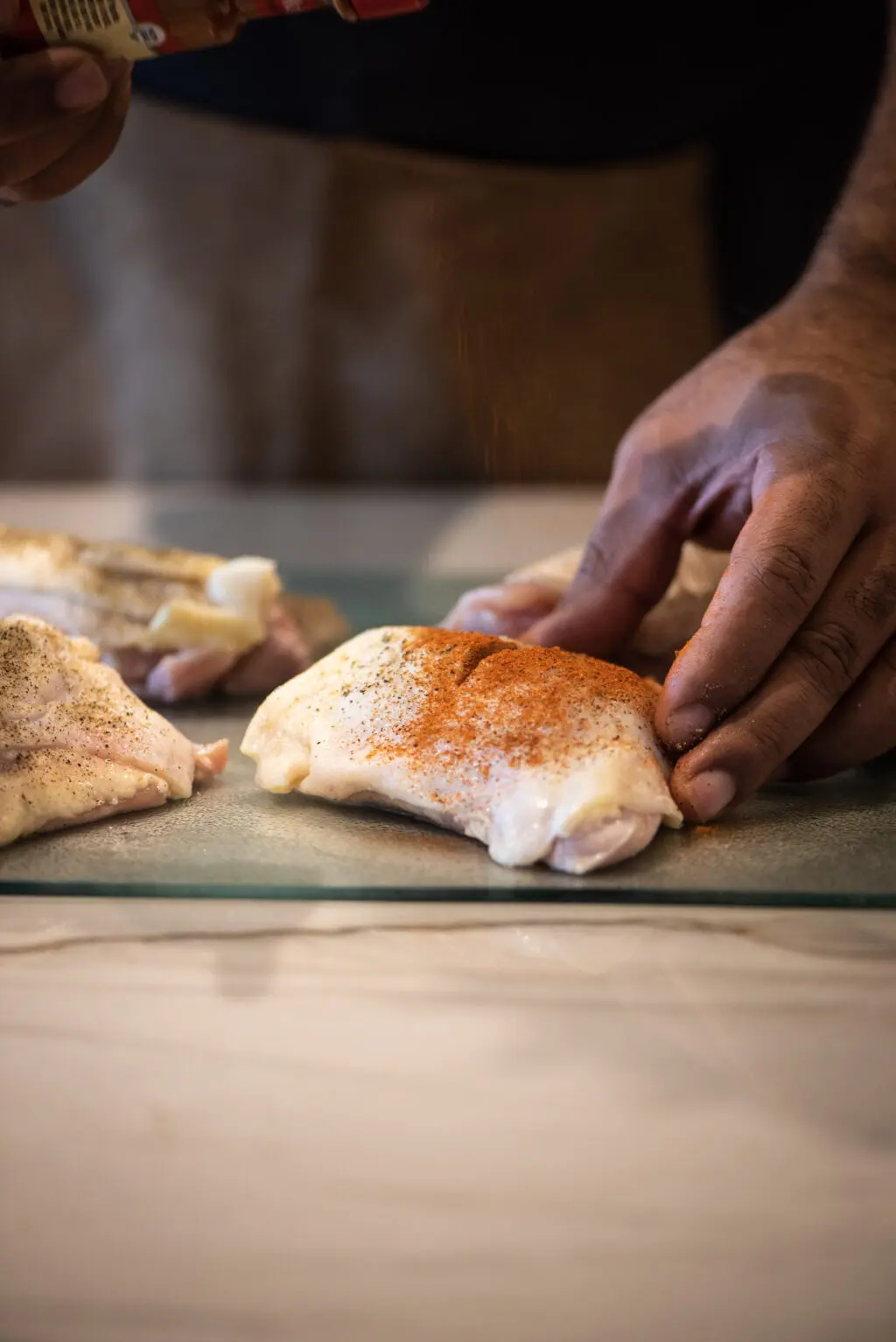 Seasoning and cutting a silt in the top of each chicken thigh
