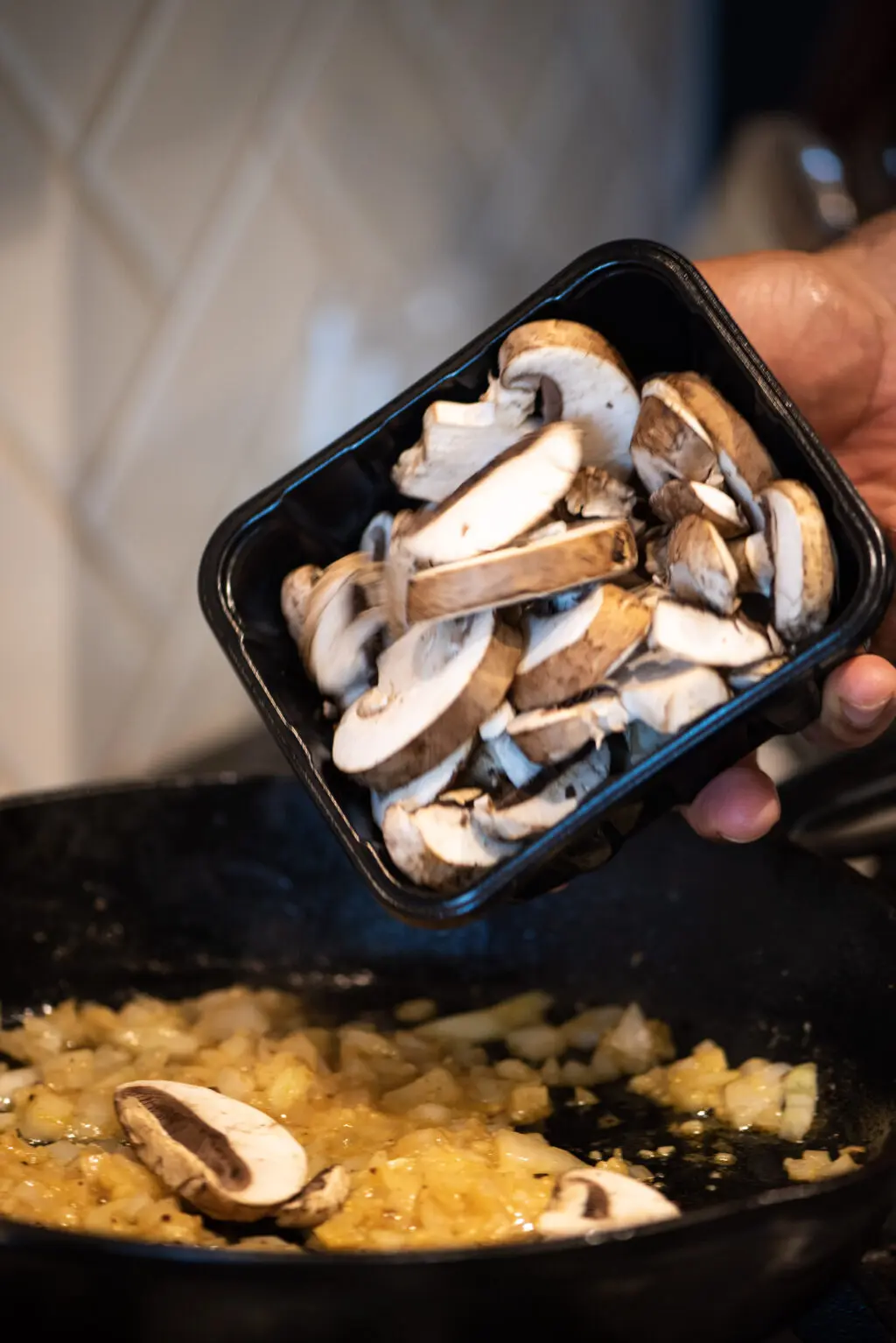 Adding fresh mushrooms to a skillet