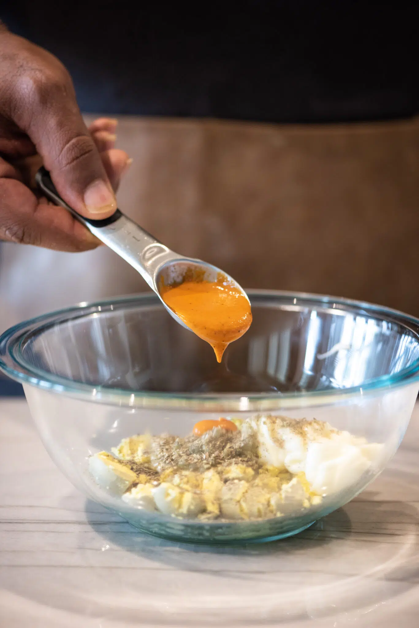 Adding buffalo sauce to deviled eggs mixture