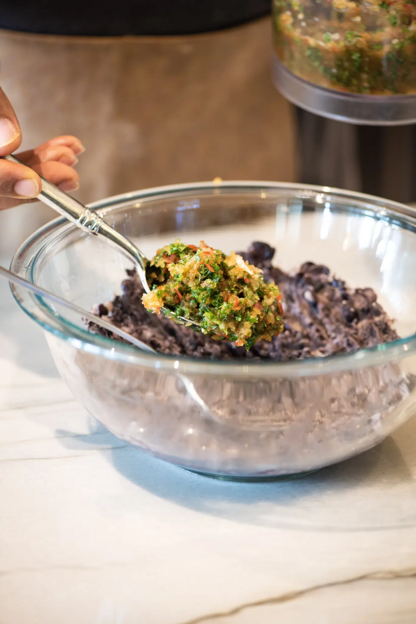 Adding chopped red bell peppers, onion, and cilantro to the smashed black beans.