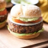 Black bean burger with avocado and other condiments in the background