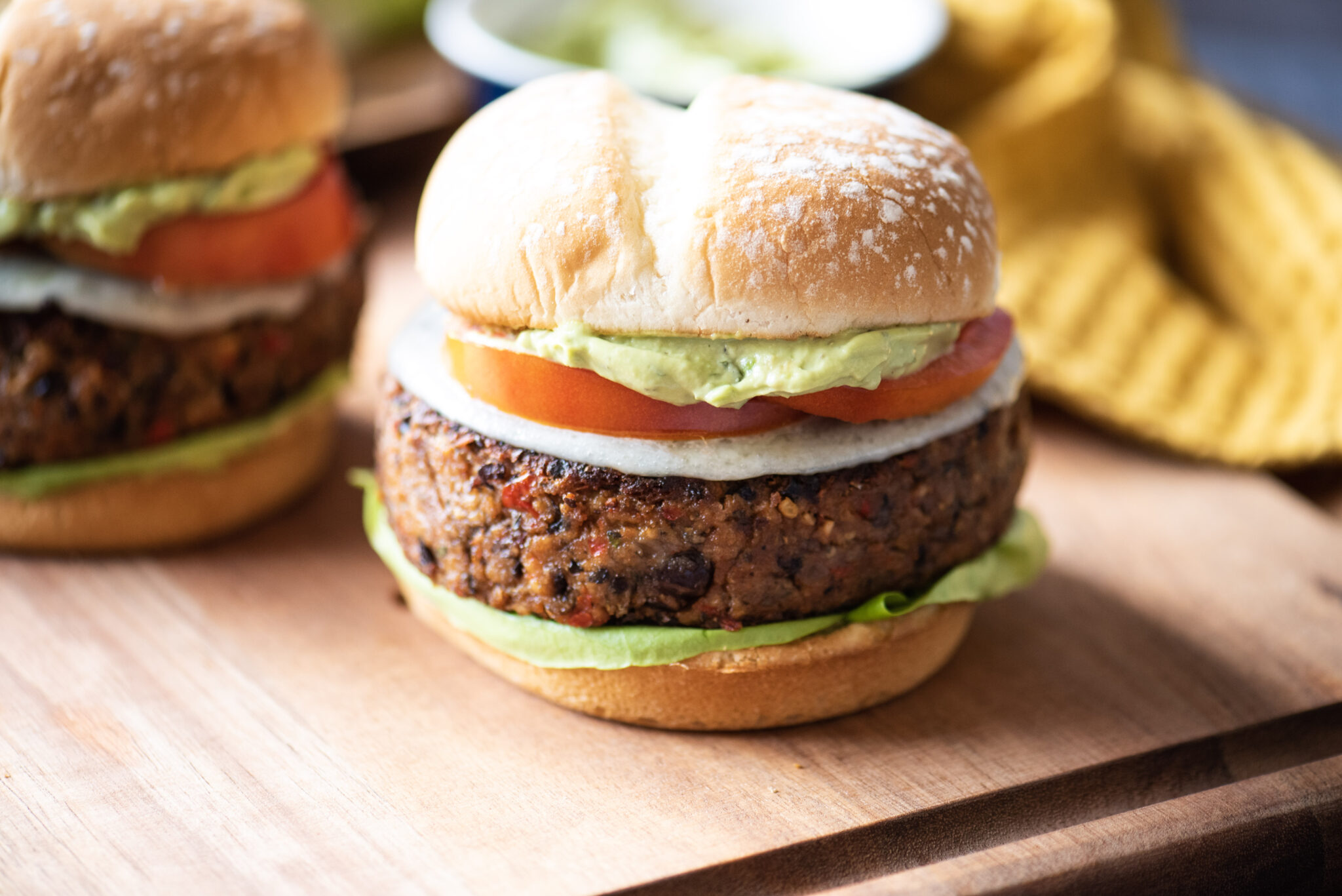 Black bean burger with avocado and other condiments in the background