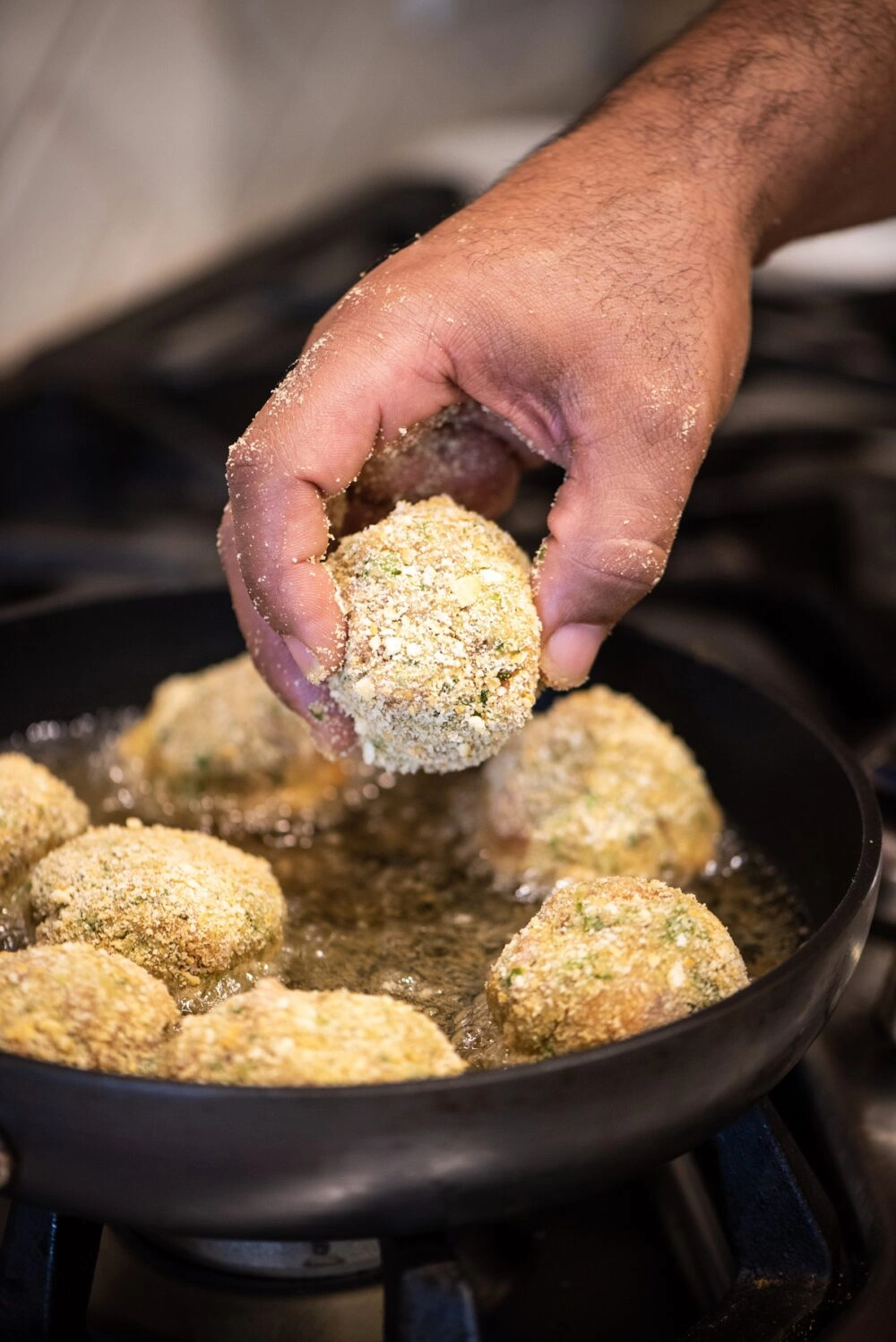 Placing croquettes into frying pan