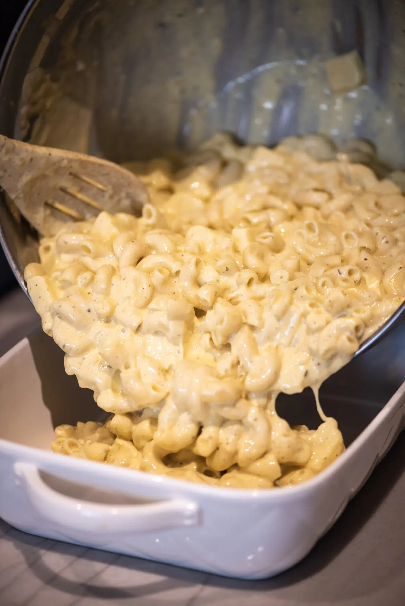 Pouring mac and cheese mixture into casserole dish for baking