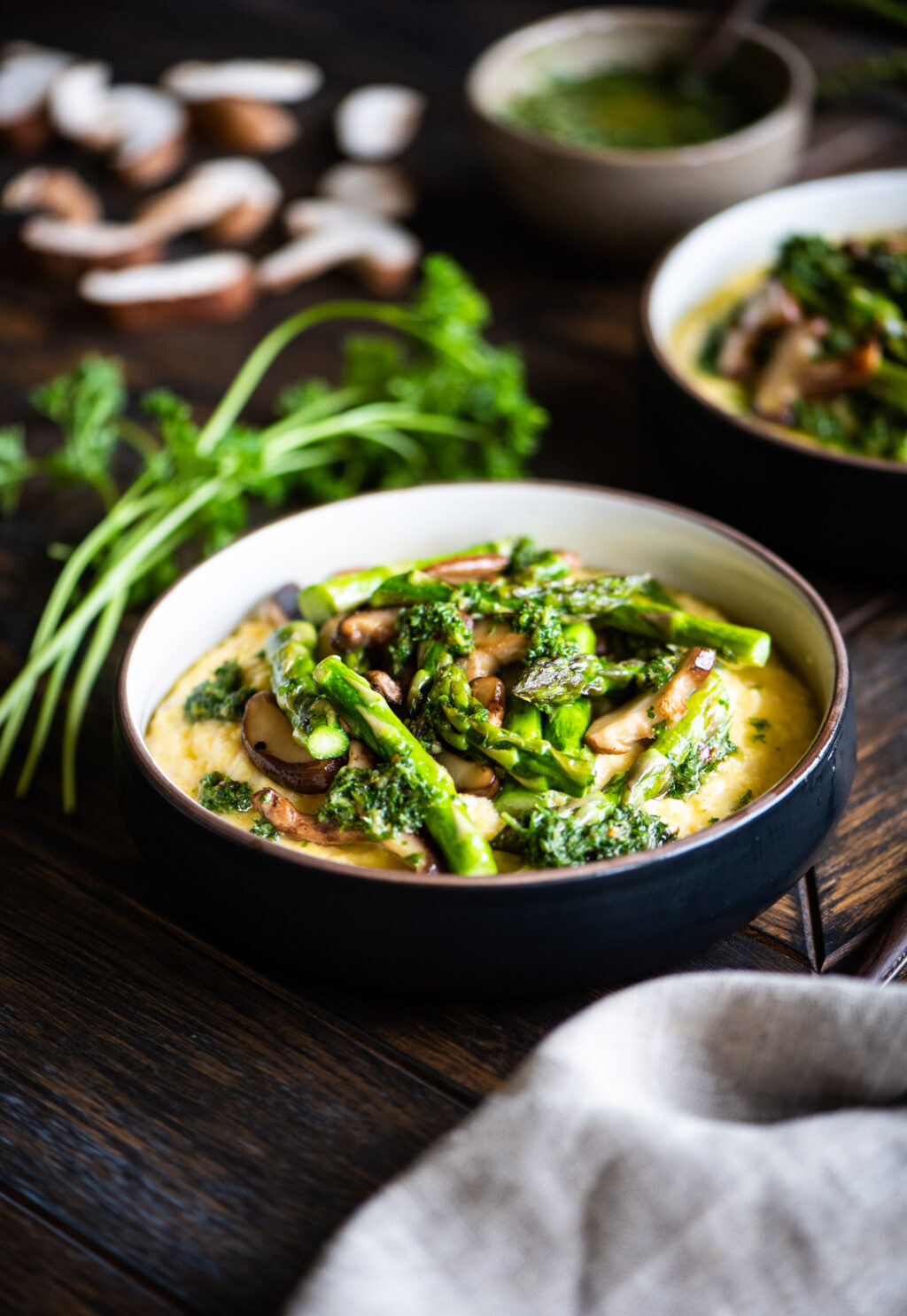 cheesy polenta and spring veggies surrounded by fresh mushrooms, asparagus, and parsley