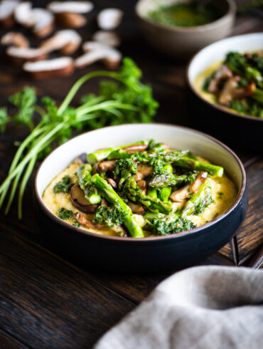cheesy polenta and spring veggies surrounded by fresh mushrooms, asparagus, and parsley