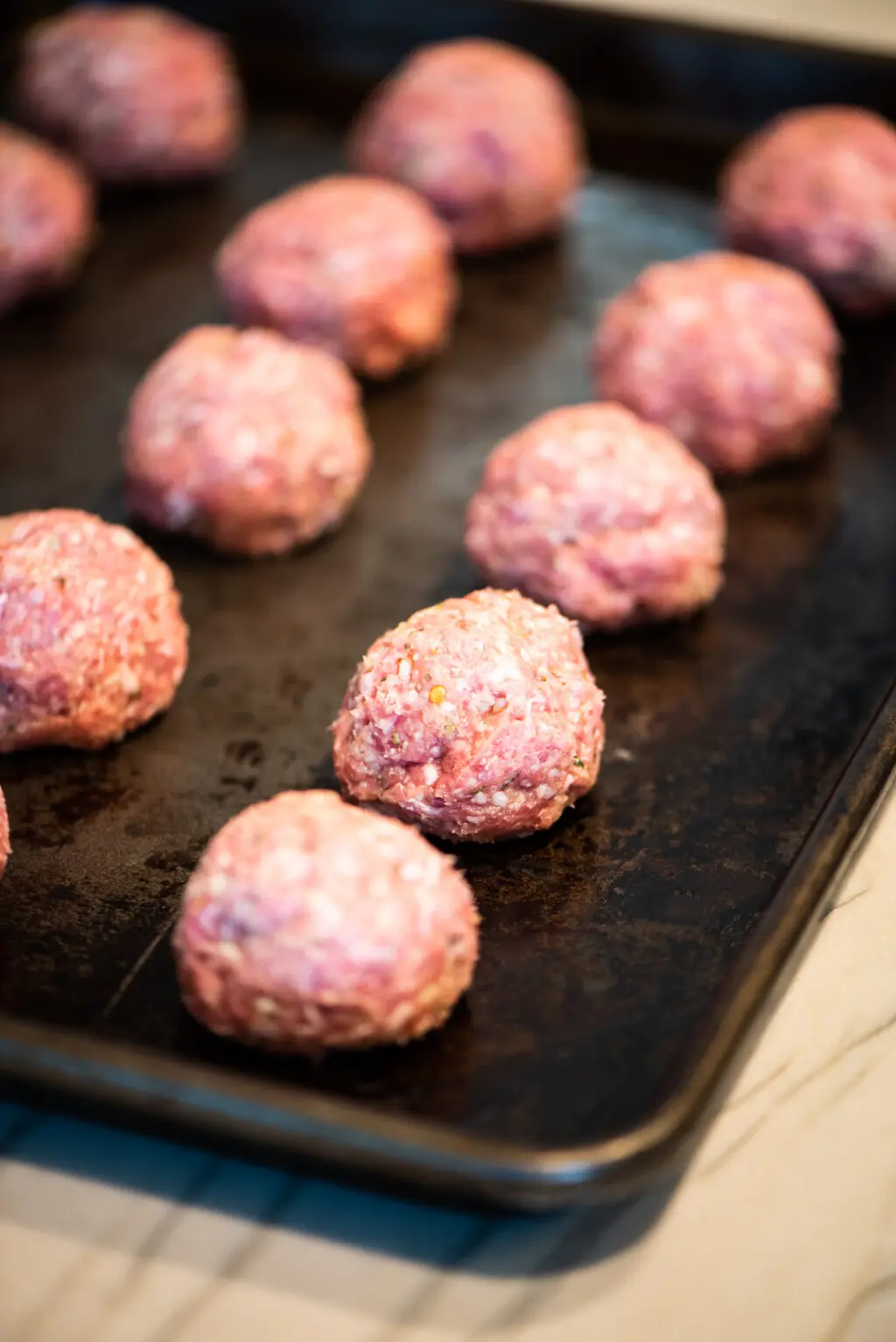 Placing lamb meatballs on baking sheet before baking in oven