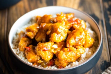 side shot of sweet and sour chicken served with rice and black chopsticks
