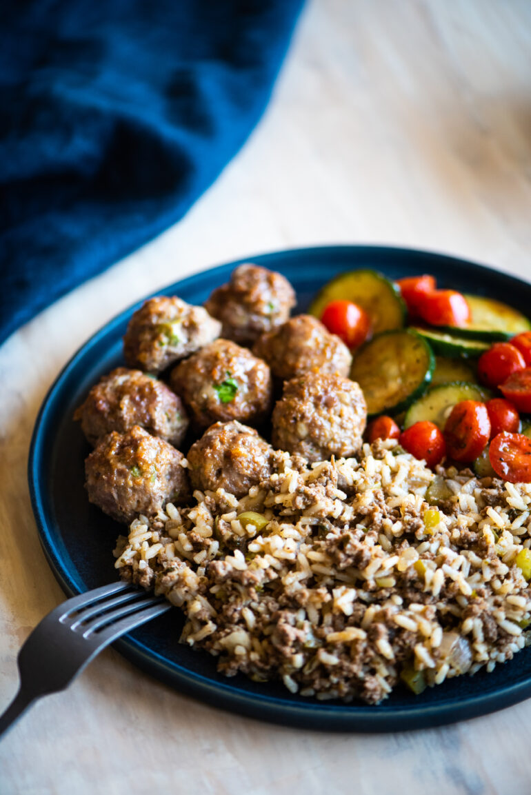 Plate of cajun meatballs, dirty rice, and a cucumber salad for meal prep