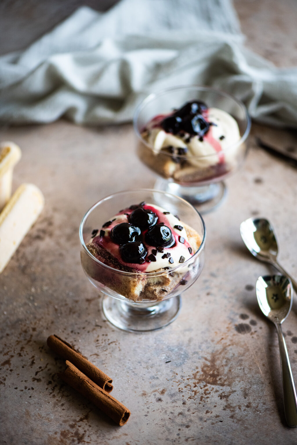 two glass bowls of deconstructed tiramisu topped with cocktail cherries