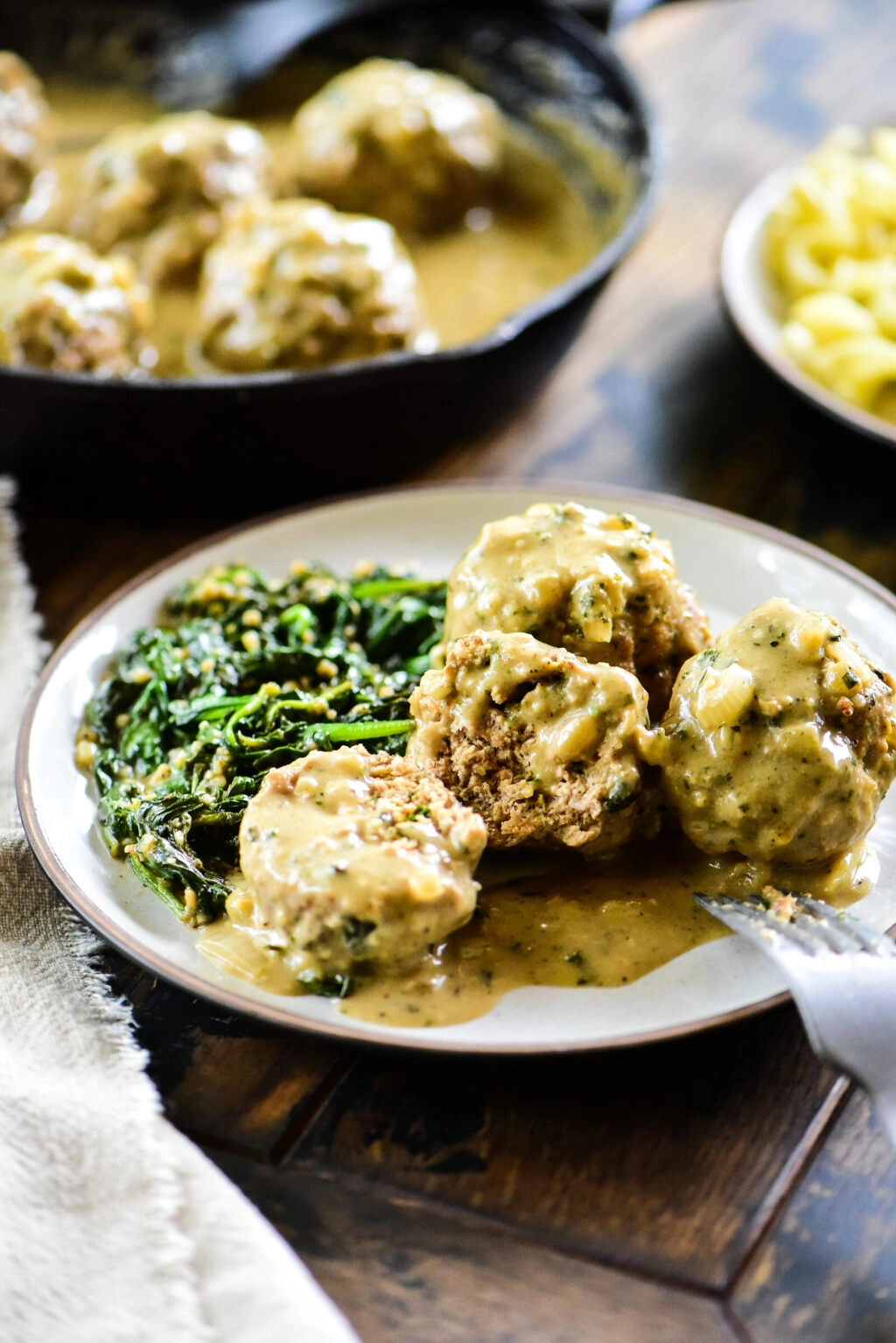 turkey meatball cut open with fork and served with sauteed spinach
