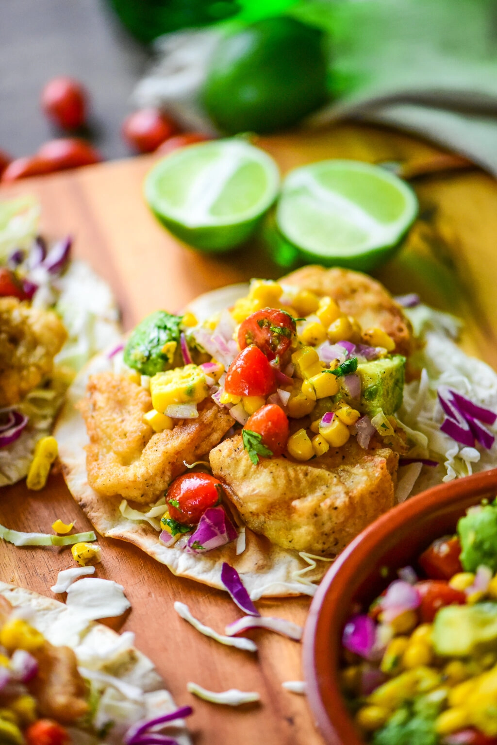 single crispy fish taco topped with corn salsa