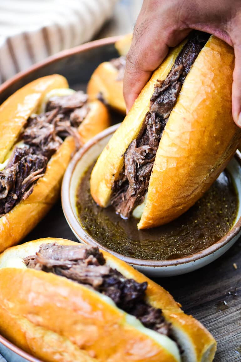 dipping French dip sandwich in au jus