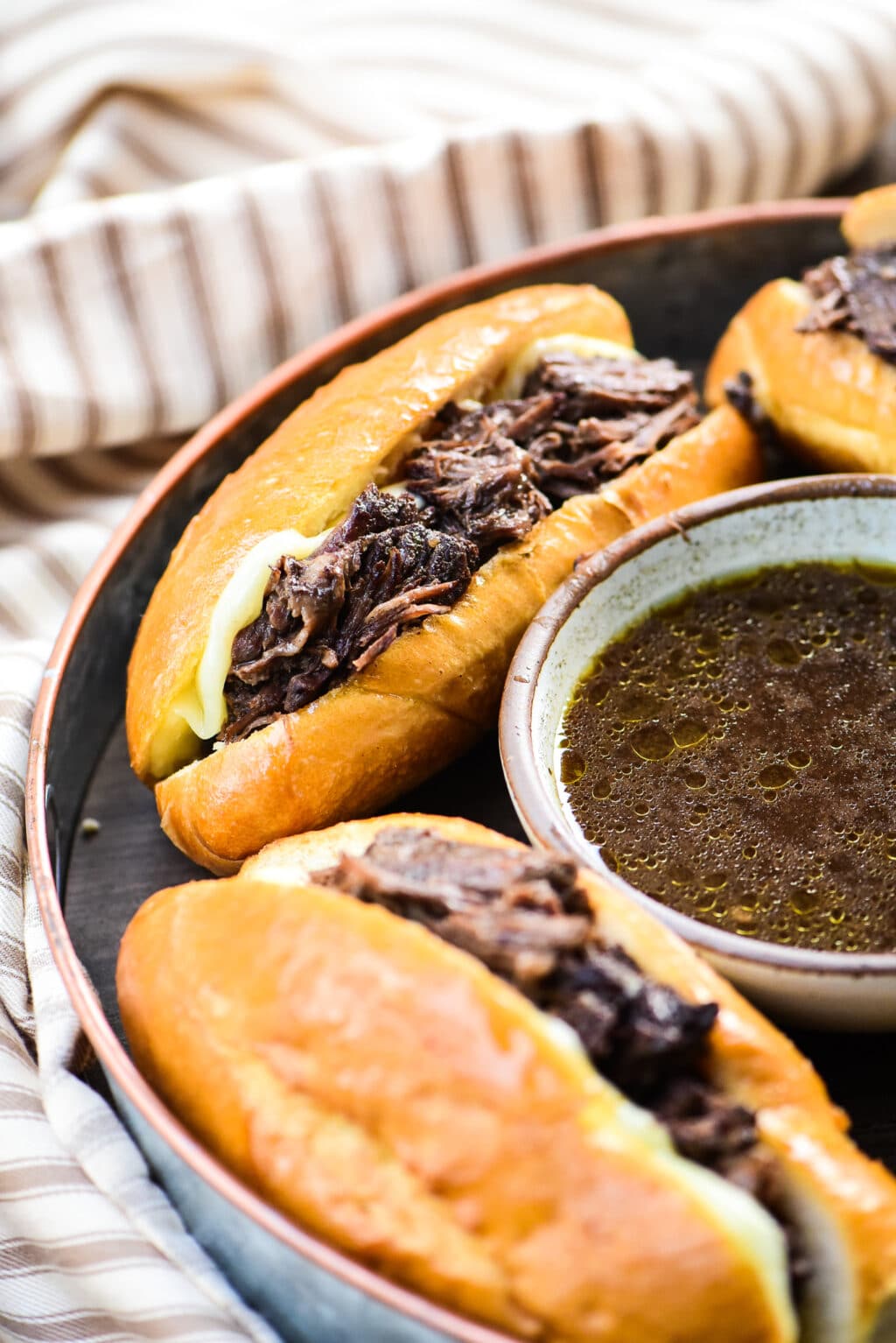 round serving plate with French dip sandwiches