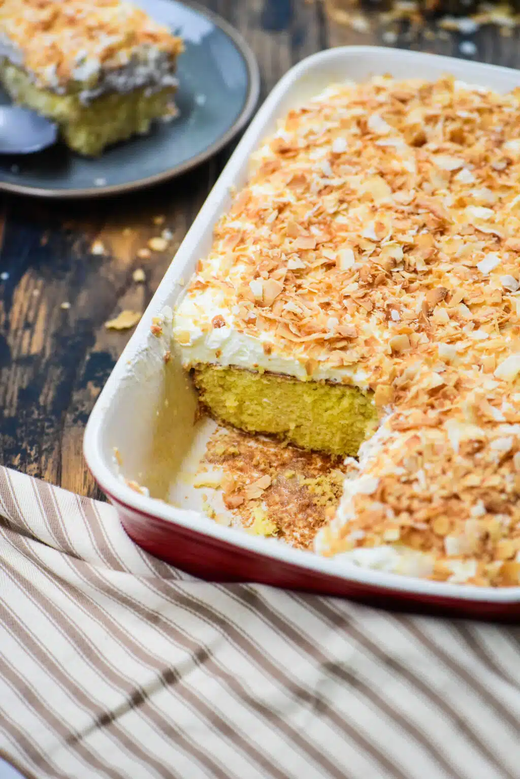 whole casserole of coconut tres leches cake with a piece cut out